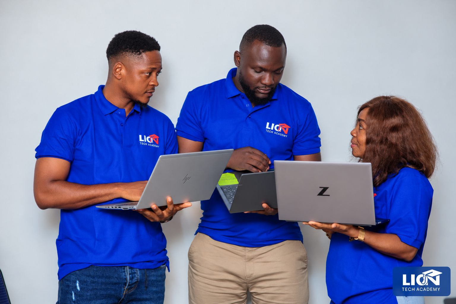 LionTech Academy team members offering student guidance with laptops